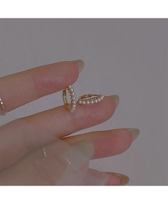 Close-up of golden pearl hoop earrings held by hand to show size and quality