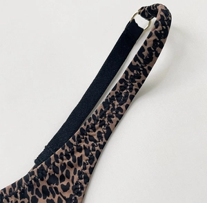 Détail du string imprimé léopard avec anneau en métal doré et bandoulière noire élastique