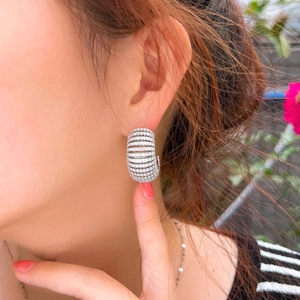 Close-up of C-shaped striped hollow earrings with colorful gradient cubic zirconia stones