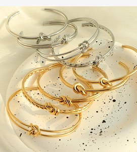 Vista dettagliata dei bracciali rigidi a nodo in oro e argento dal design lucido e ritorto