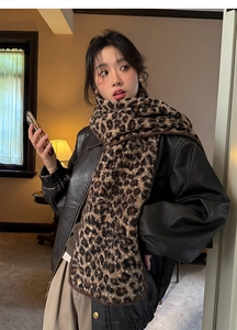 Detail of warm brown leopard print scarf styled with a black leather jacket in a retro setting