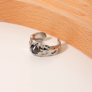 Minimalist silver open ring with black zircon stone and irregular texture on white wood