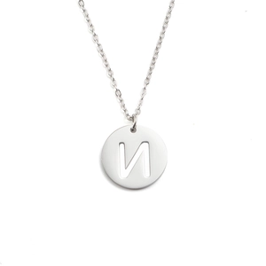 Gros plan d'un pendentif rond argenté avec la lettre N sur une chaîne en acier inoxydable