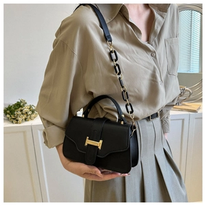 Detail view of black matte leather bag with golden H clasp worn by model