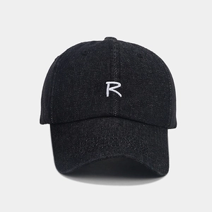 Detailed view of white embroidered R letter on dark indigo denim baseball cap texture