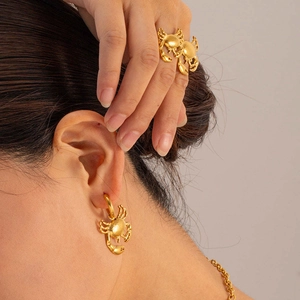 Close-up of gold-plated stainless steel crab hoop earrings and adjustable ring on model