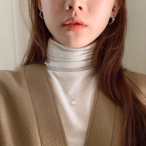 Detail of silver geometric square necklace and twisted gold hoop earrings on model