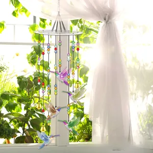 Hanging DIY hummingbird suncatcher with colorful beads and metal bells near a window