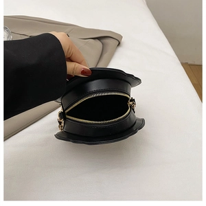 Detail view of the gold zipper opening on this unique black hat-shaped crossbody bag