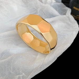 Macro shot of gold-plated geometric chunky bangle with textured honeycomb faceted design