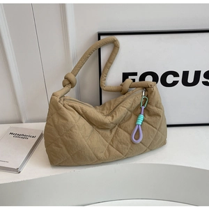 Detail of khaki quilted tote bag featuring a knotted strap and colorful decorative zipper pull
