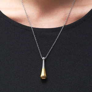 Close-up of model wearing gold baseball bat pendant urn necklace with silver chain