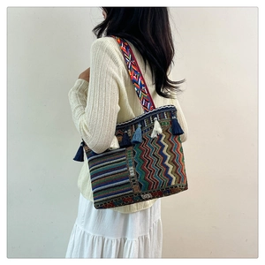 Detailed close-up of ethnic woven bag with colorful geometric patterns and tassel trim
