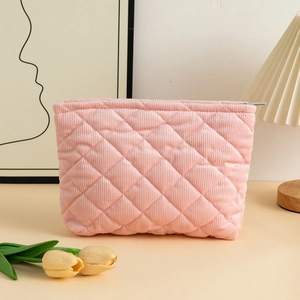 Detailed view of pink corduroy makeup bag with quilted diamond pattern and gold zipper