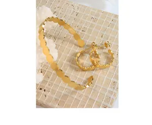 Detail of gold minimalist jewelry set with brushed metal texture and wavy oval design