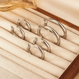 Three pairs of polished stainless steel hoop earrings in graduated sizes for men and women