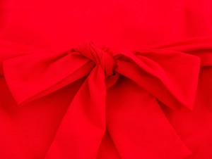 Detail der roten Stofftextur und einer gebundenen Schleife an einem ärmellosen Kleid