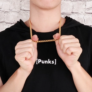 Détail d'un collier chaîne box dorée résistante porté par un mannequin homme sur noir