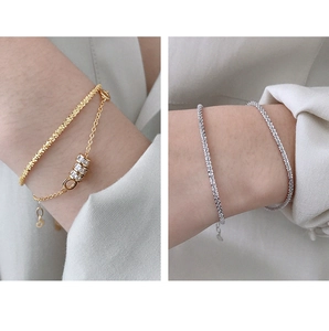 Close-up of S925 sterling silver bracelets with layered gold chains and sparkling crystals
