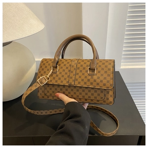 Detail of a brown trapezoid handbag with circular patterns and golden metal hardware