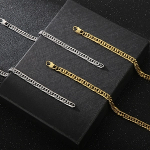 Detail of gold and silver cuban link chains with lobster clasps on a black jewelry box