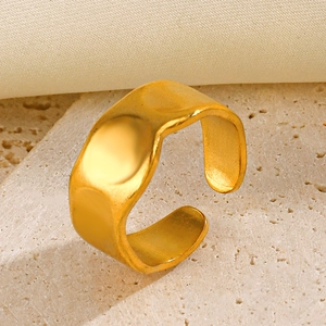 Irregular wide wave open ring in gold finish on a minimalist stone display stand