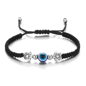 Detail of evil eye charm and silver flower beads on a black woven adjustable bracelet