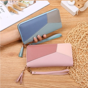 Close-up of geometric patchwork leather wallet with zipper closure and tassel detail