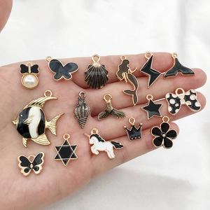 Assorted black and gold enamel charms including butterflies stars and shells on palm