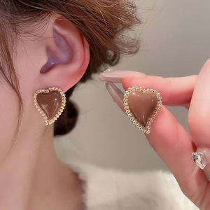Detail of vintage heart earrings with coffee resin and gold lace edges on model