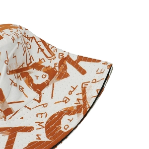 Dettaglio della trama del tessuto e delle scritte graffiti arancioni sul cappello bianco