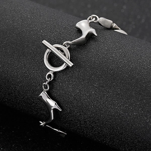 Bracelet en acier titane argenté avec fermoir OT et breloques oiseau sur fond noir