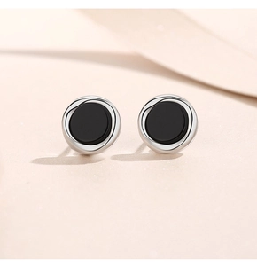Macro shot of minimalist S925 sterling silver stud earrings with black onyx inlay