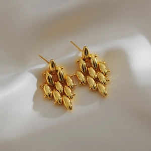 Detailed view of golden multi-layer teardrop beaded diamond-shaped earrings on white silk