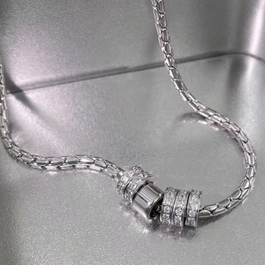 Macro shot of silver woven chain necklace with sparkling pavé diamond rings and cylinder