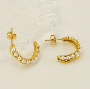 Macro detail of 18K gold-plated C-shape earrings featuring inset white pearls and butterfly back