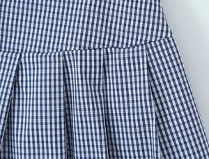 Macro view of blue and white gingham pleated fabric texture with detailed stitching