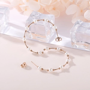 Macro view of C-shaped rose gold pearl hoop earrings with elegant floral background