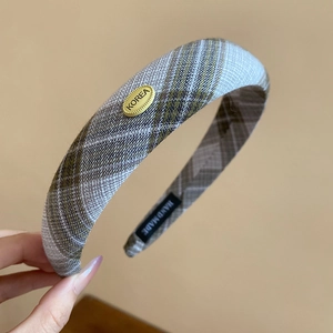 Detailed close-up of brown-grey plaid thick headband with gold Korea logo metal plate