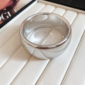Macro shot of silver metal wide bangle with geometric diamond patterns on white display
