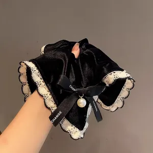 Detail of velvet scrunchie with lace edge, ribbon bow and pearl pendant accessory