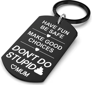 Macro shot of black shield-shaped stainless steel keychain with engraved motivational quotes