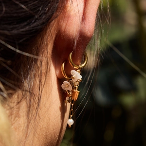 Gros plan détaillé de boucles d'oreilles en or 18K avec fleurs blanches et perles sur modèle