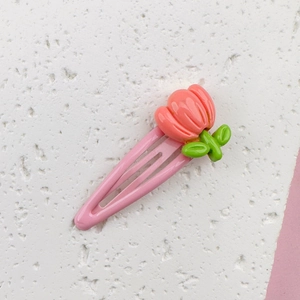 Detail of pink metal snap clip with resin coral tulip and green leaf ornament