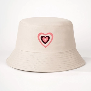 Dettaglio del cappello a secchiello beige con stampa a cuore e trama in twill di cotone