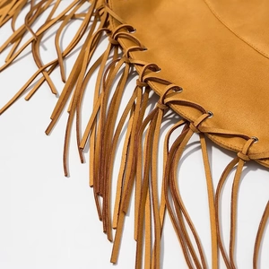 Detailed close-up of brown suede fabric featuring fringe tassels and metal eyelet details