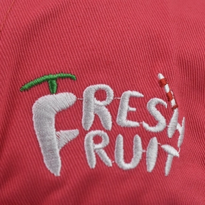 Macro detail of Fresh Fruit embroidery on a red cotton twill baseball cap fabric
