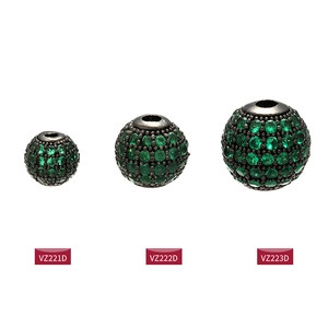 Detailed macro view of black metal round beads pavé-set with sparkling green crystals