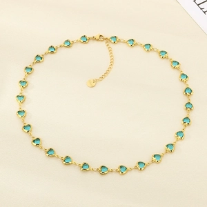 Detail of gold heart pendant with blue gemstone and S.Steel engraving tag on the necklace