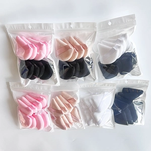 Macro shot of assorted black, pink, and white triangular velvet powder puffs in clear bags